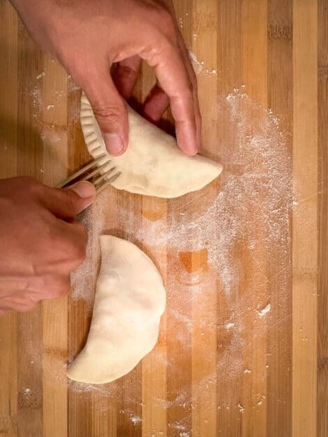 Sealing empanada discs by pressing edges with a fork.