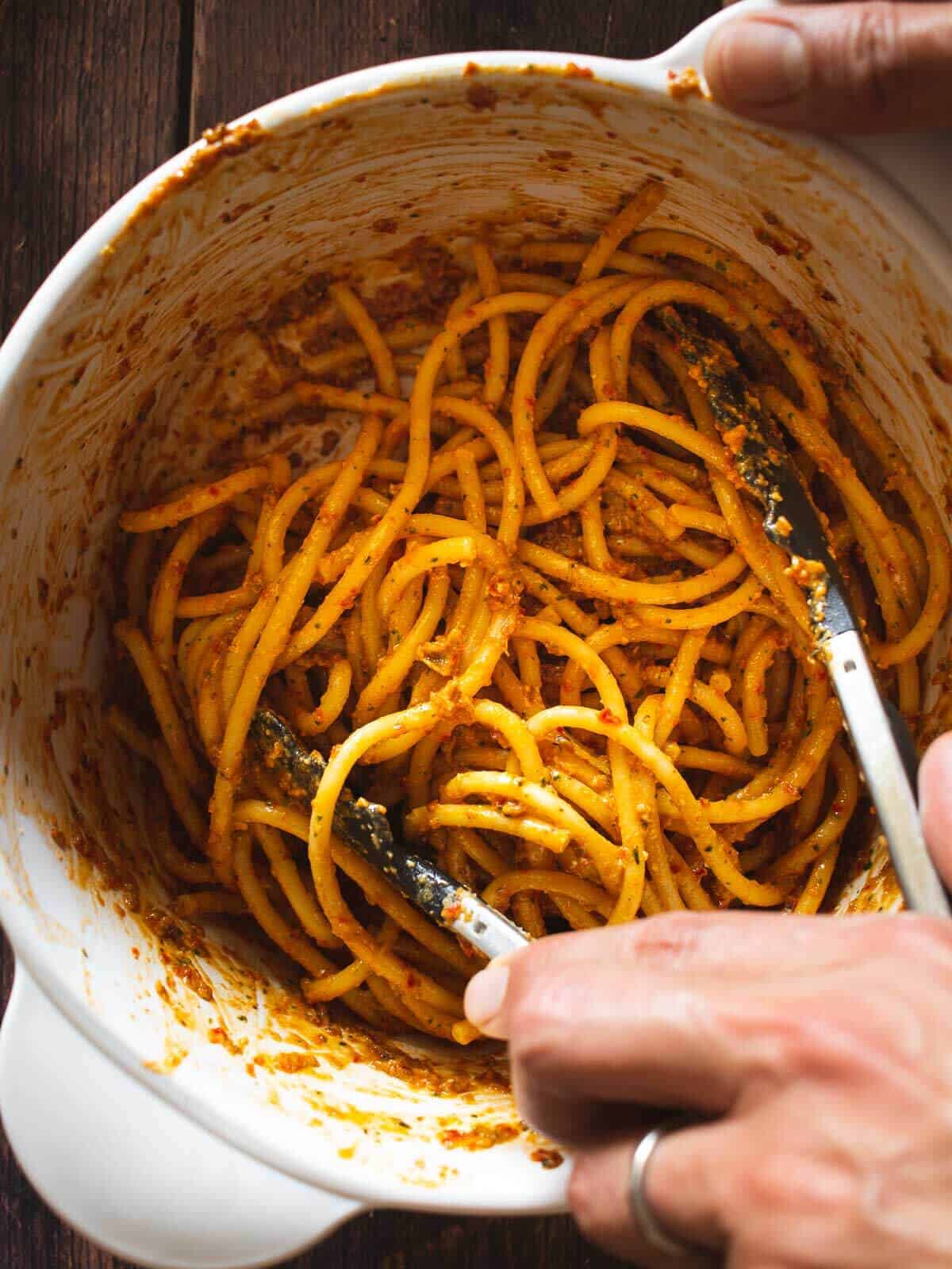 stirring pasta with sun-dried tomato pesto pasta