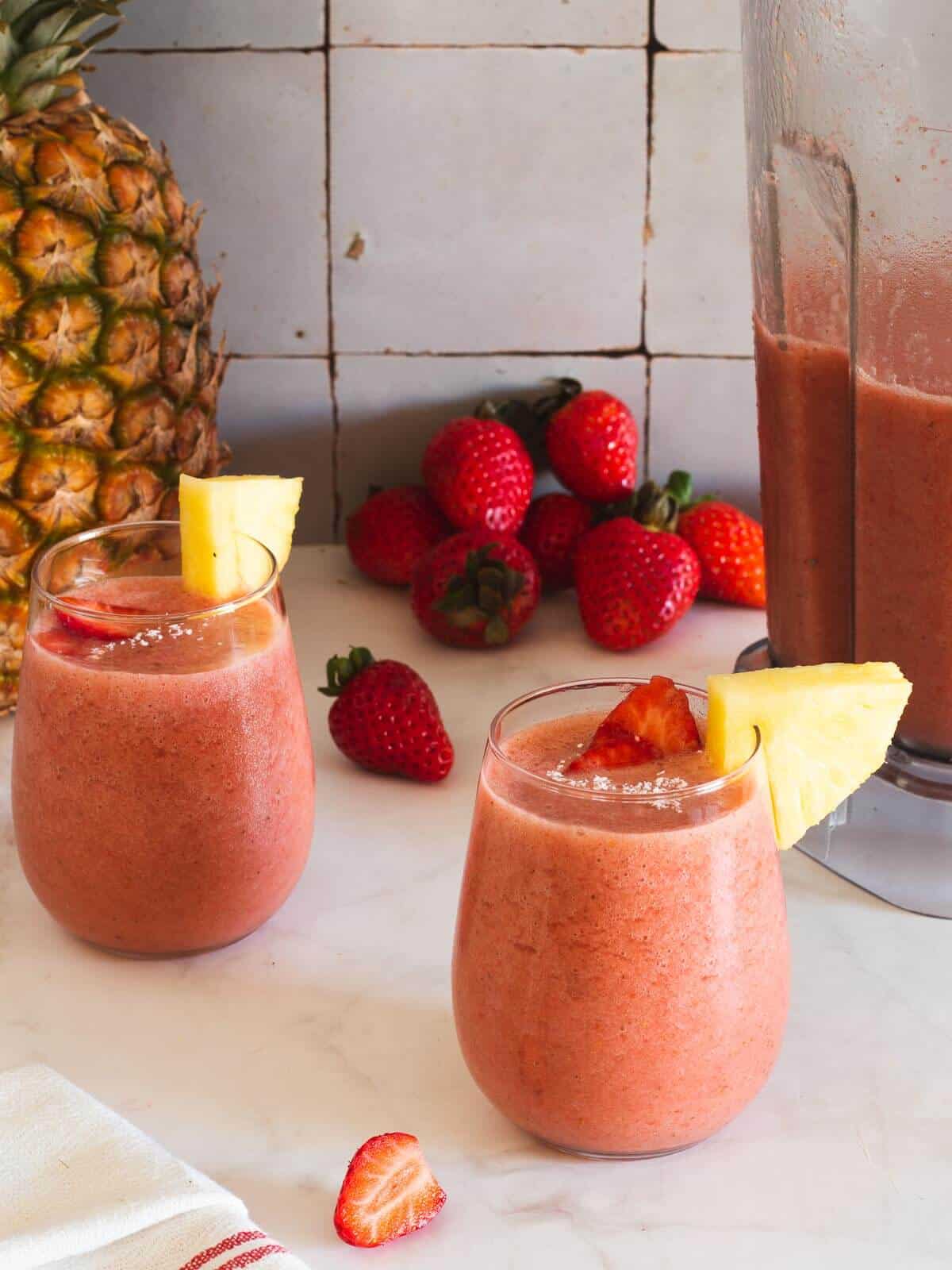 two glasses of vegan pineapple strawberry smoothie served