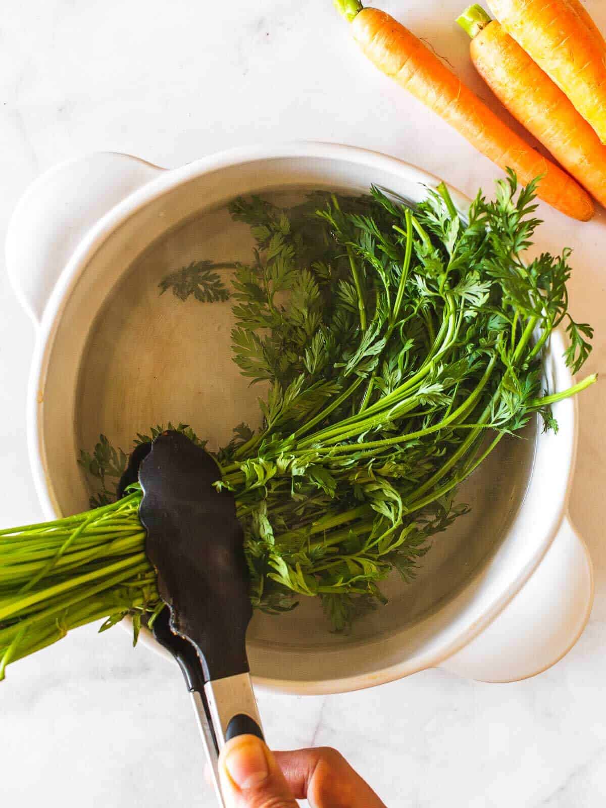 removing blanched carrot greens from hot water