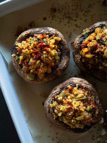 half-baked vegan stuffed portobello mushrooms with stuffing in baking sheet before baking them for the second time.