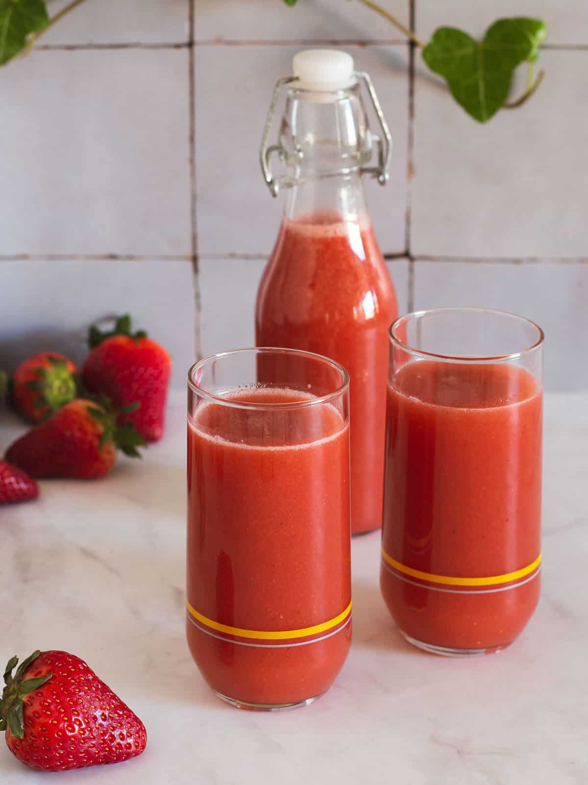 two glasses with strawberry juice and a bottled portion