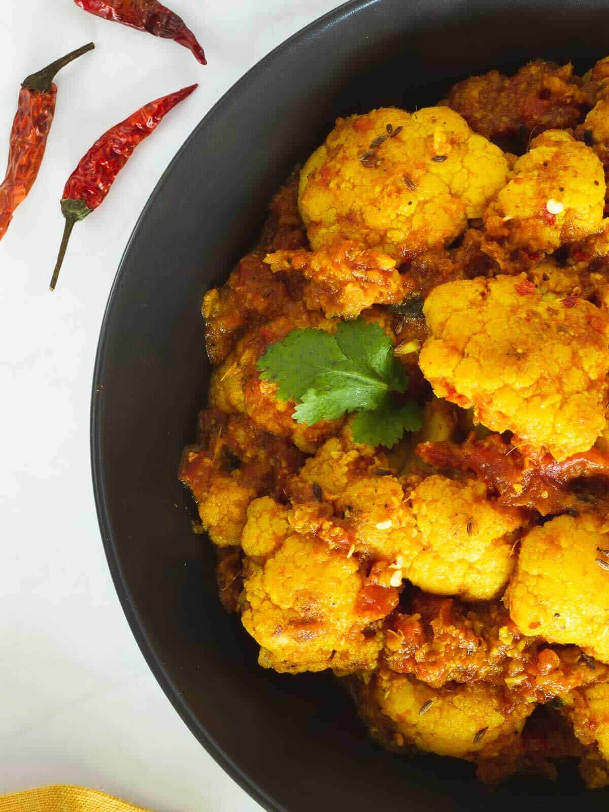 curried cauliflower plated with coriander leaves.