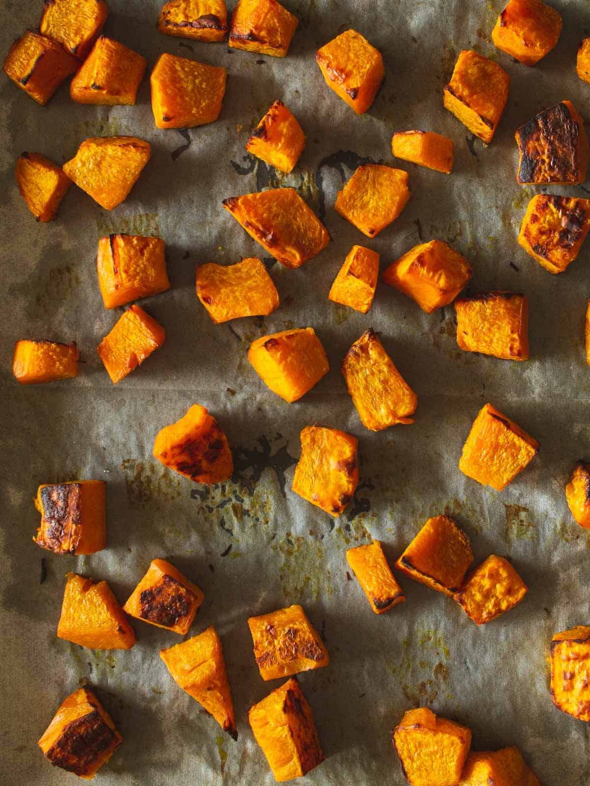 roasted pumpkin dice in a lined baking sheet