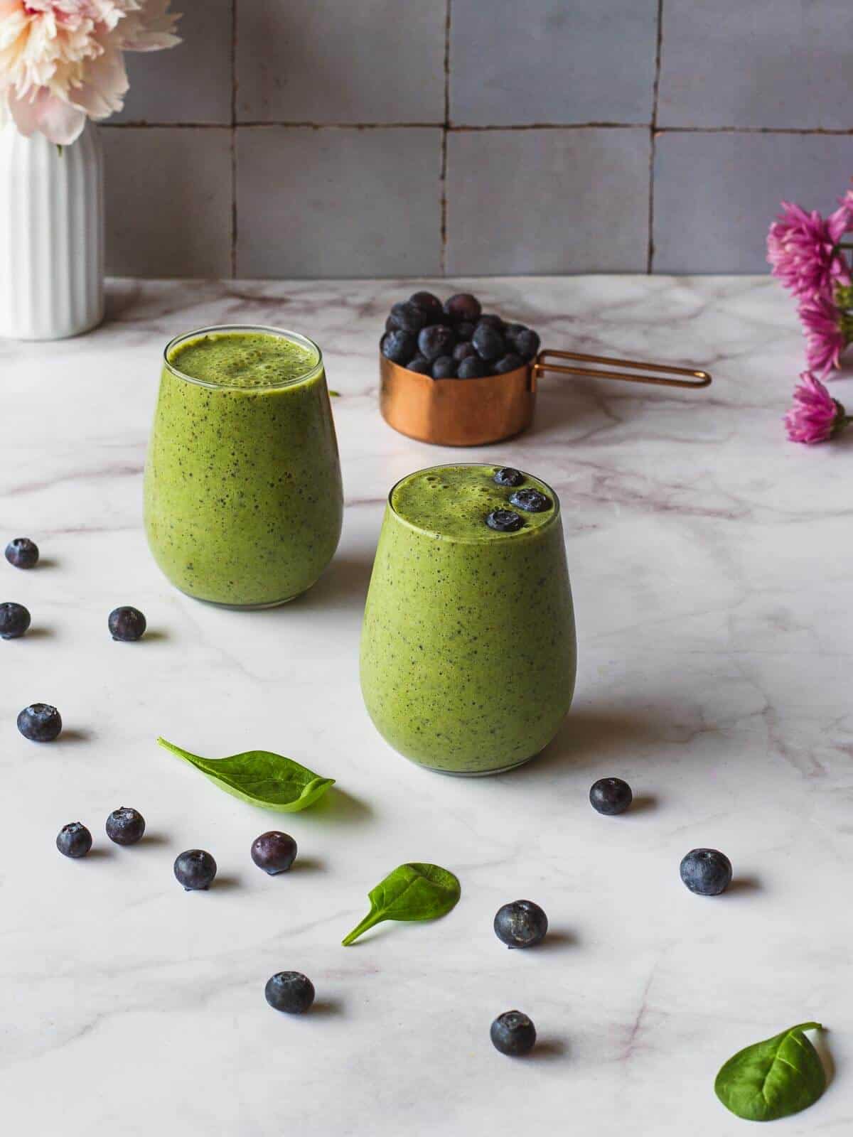 two glasses of Spinach Blueberry Banana Smoothie and a cup of blueberries