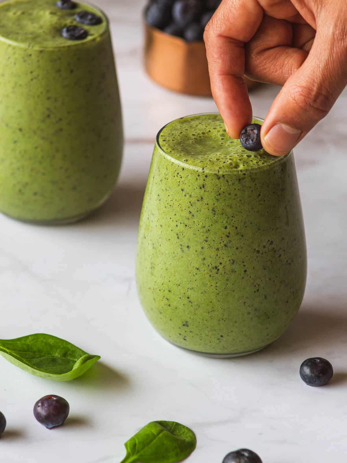 adding fresh blueberries on top of a vegan green smoothie