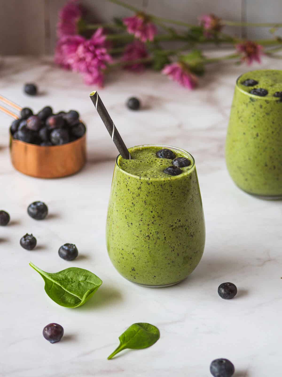 two glasses of Spinach Blueberry Banana Smoothie and a cup of blueberries