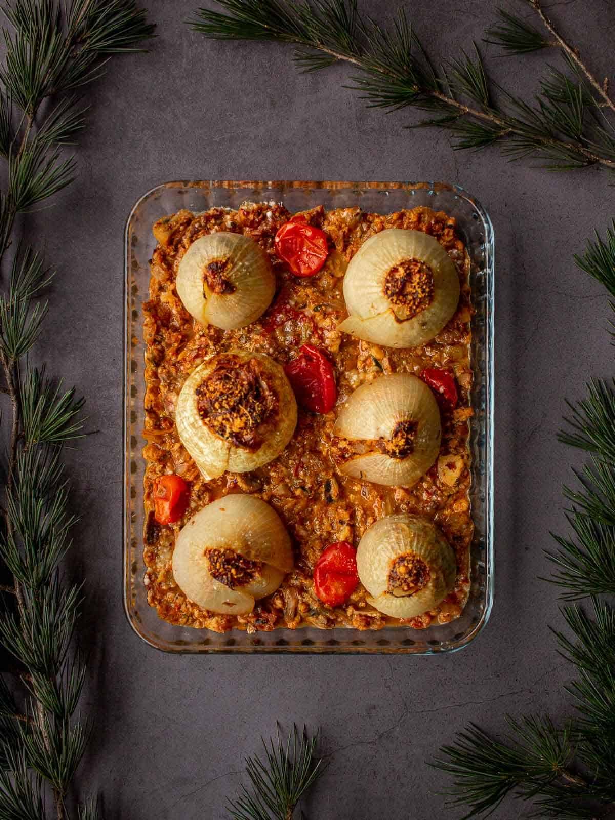 baked onions recipe plated in glass baking dish on a Christmas dinner table.