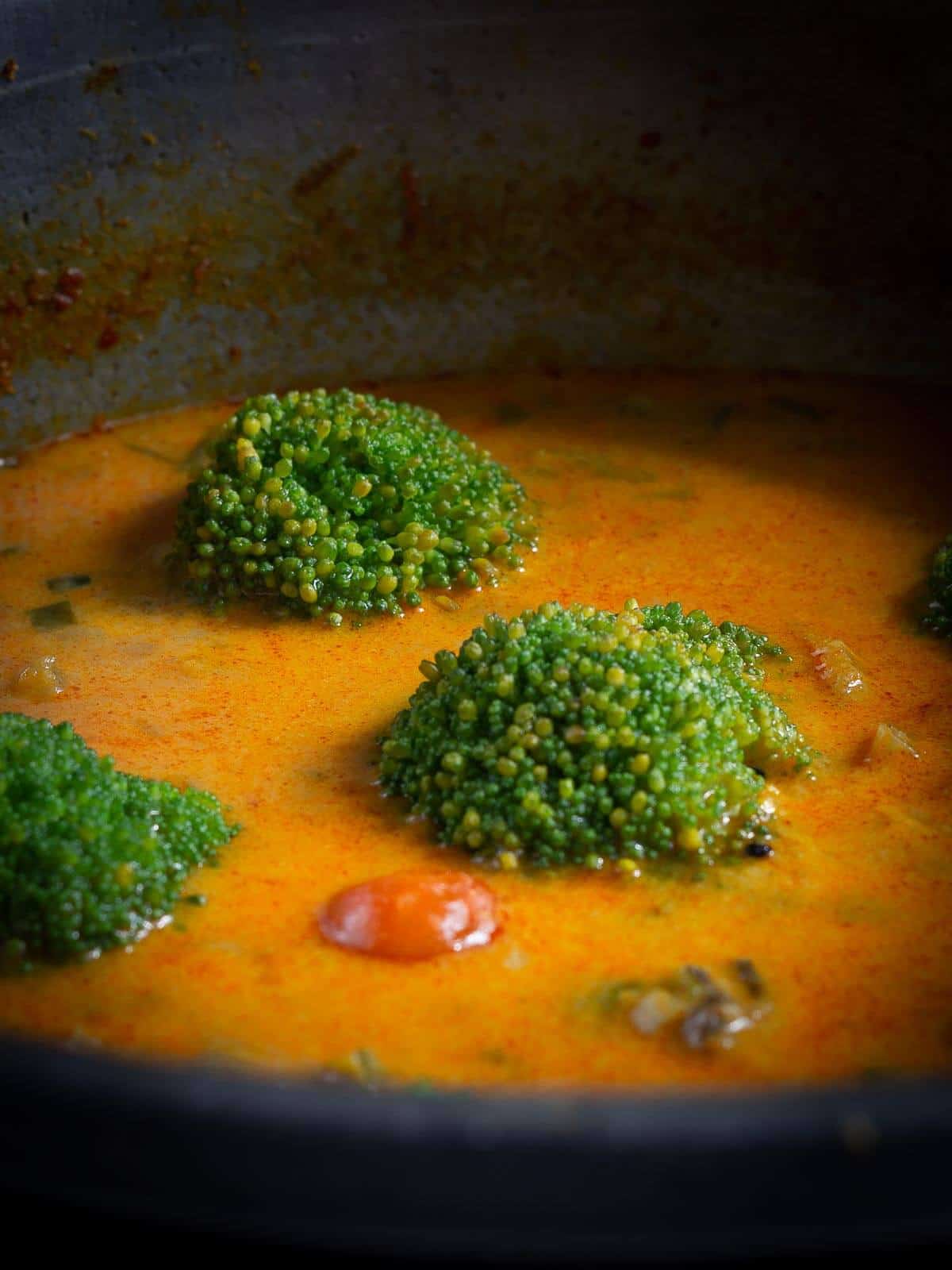 cooking curry adding broccoli florets at the very end.