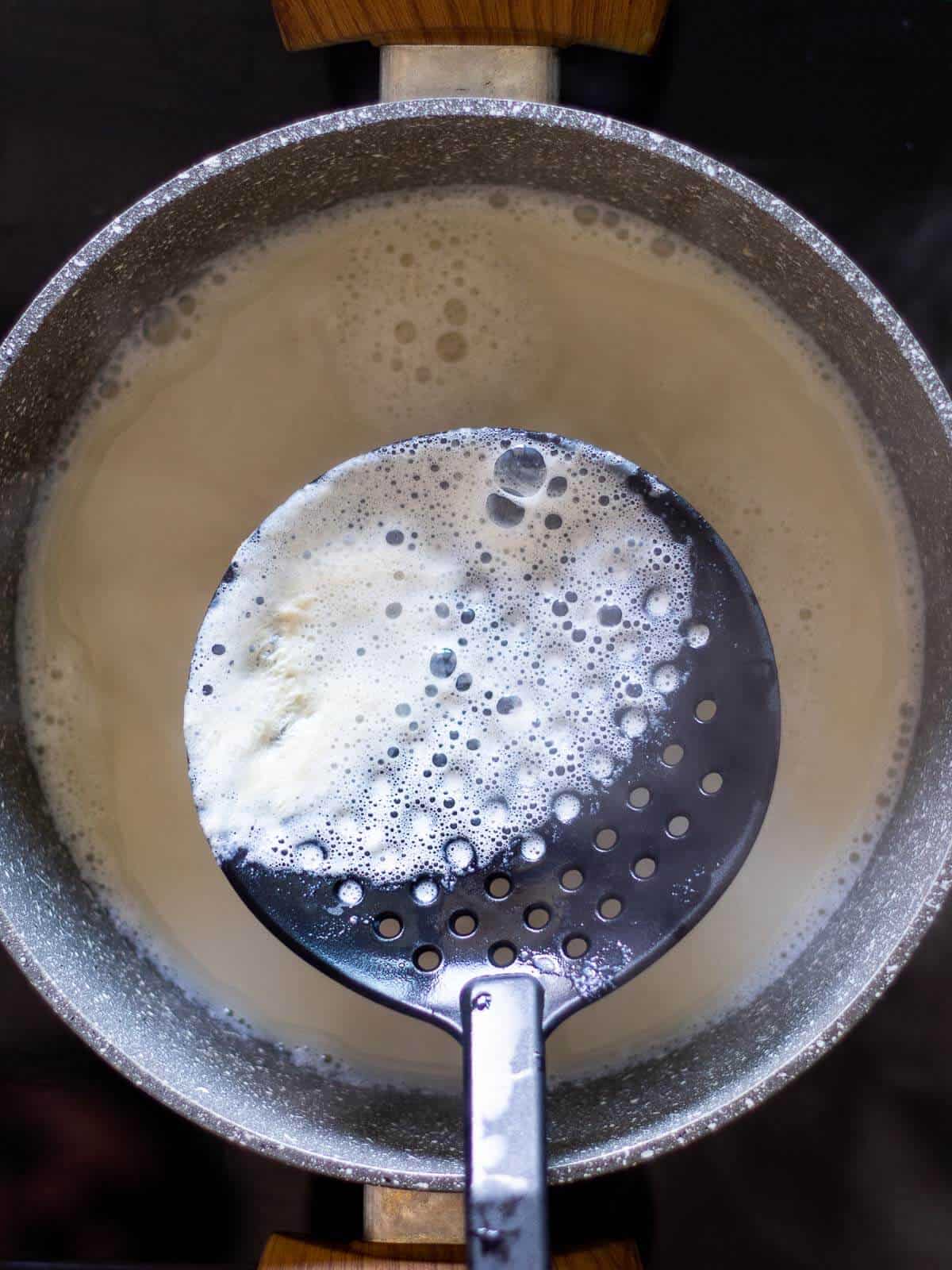 Skimming soy milk with a ladle.