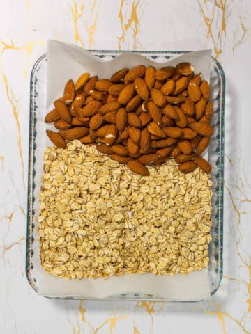 raw oats and almonds in baking sheet.