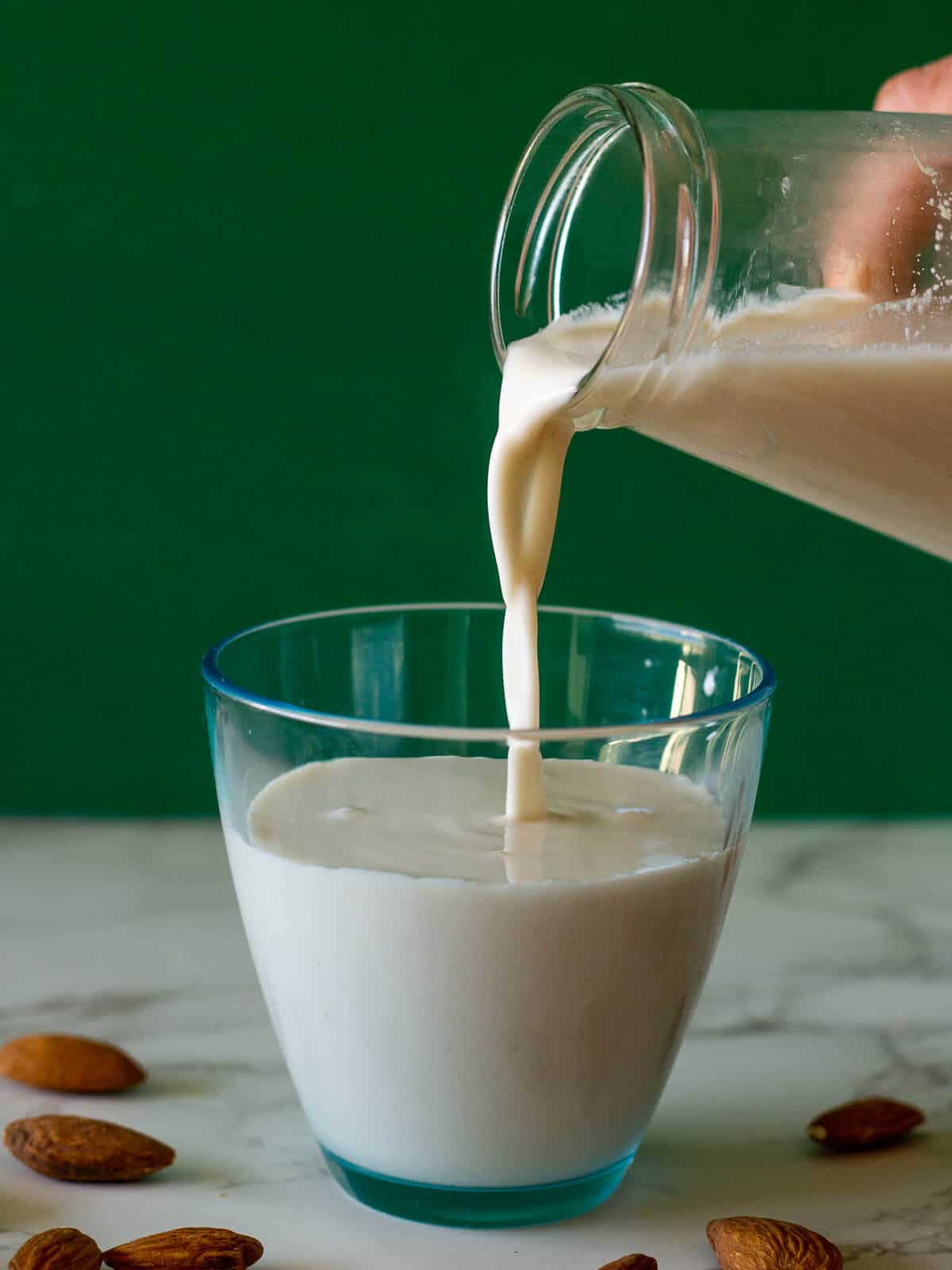 pouring DIY almond milk into a glass.