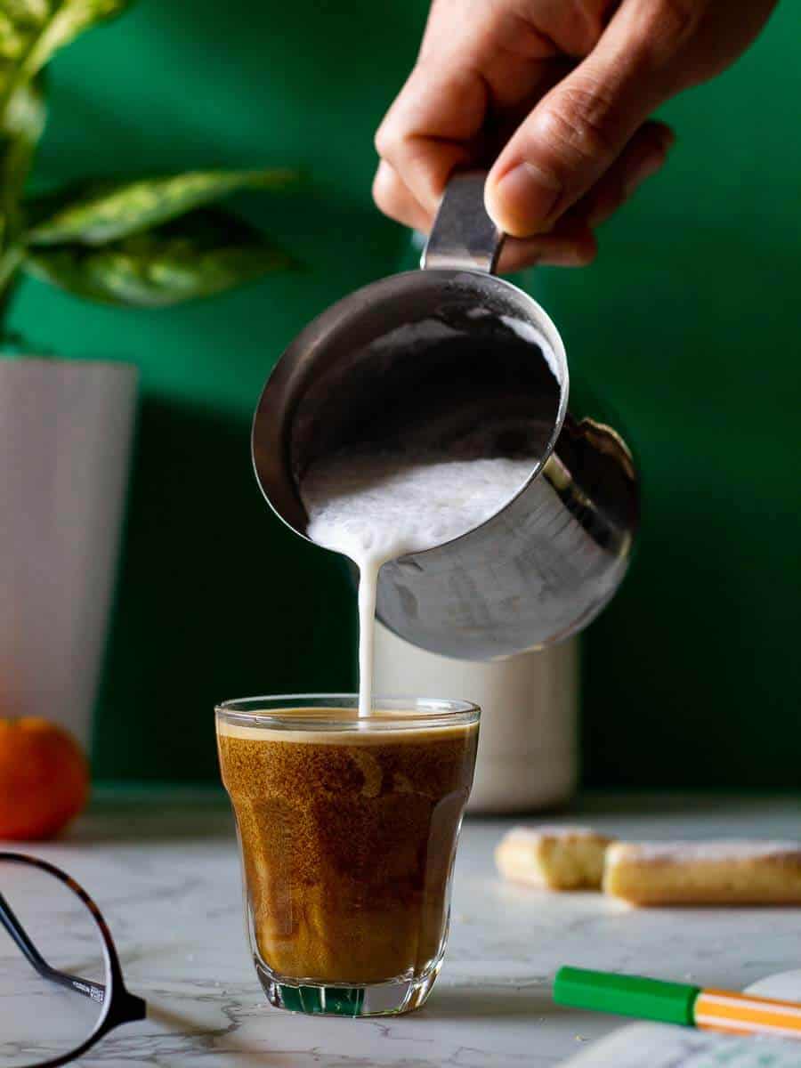 Pouring almond milk on espresso