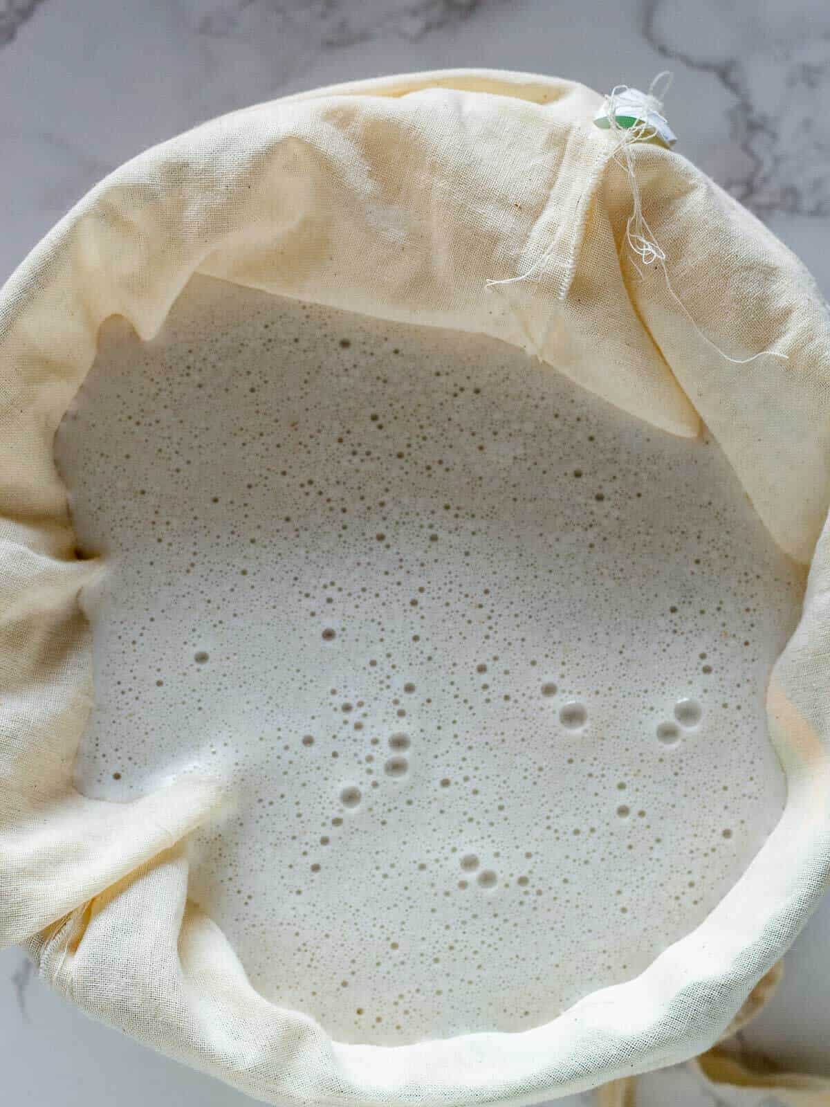 pouring blended ingredients over a nut milk cloth.