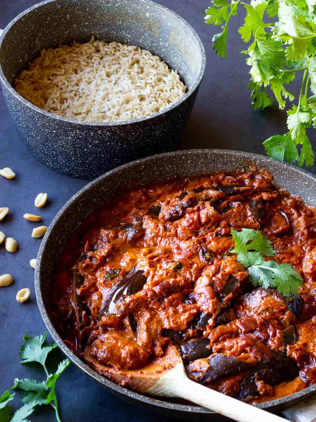 Indian Eggplant Curry with a wooden spoon in a skilet.