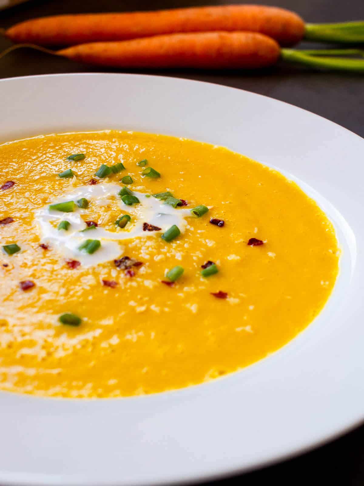 carrot and ginger soup coconut milk plate garnished with coconut milk and red pepper flakes.