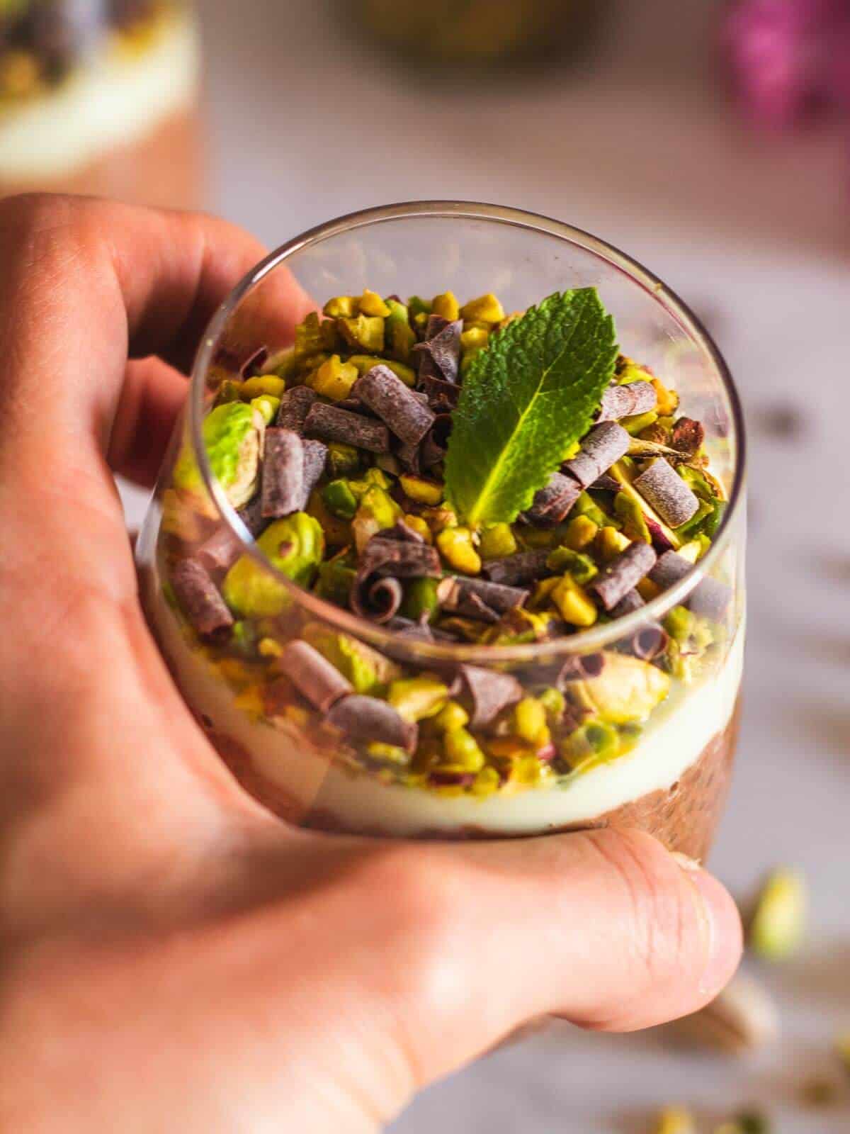 hand holding a high-protein chia pudding with cocoa nibs and pistachio
