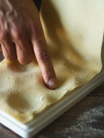 stretch the pasta sheet over the pasta tray and gently press the dough to make room for the filling.