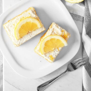 vegan lemon bars decorated with half lemons on top with a fork