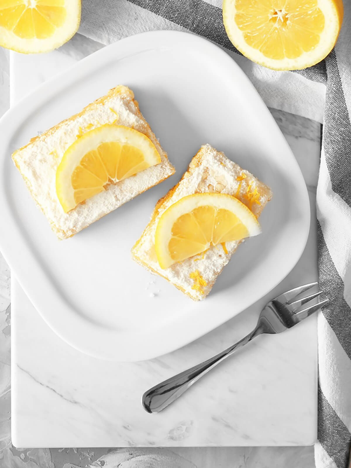 vegan lemon bars decorated with half lemons on top with a fork