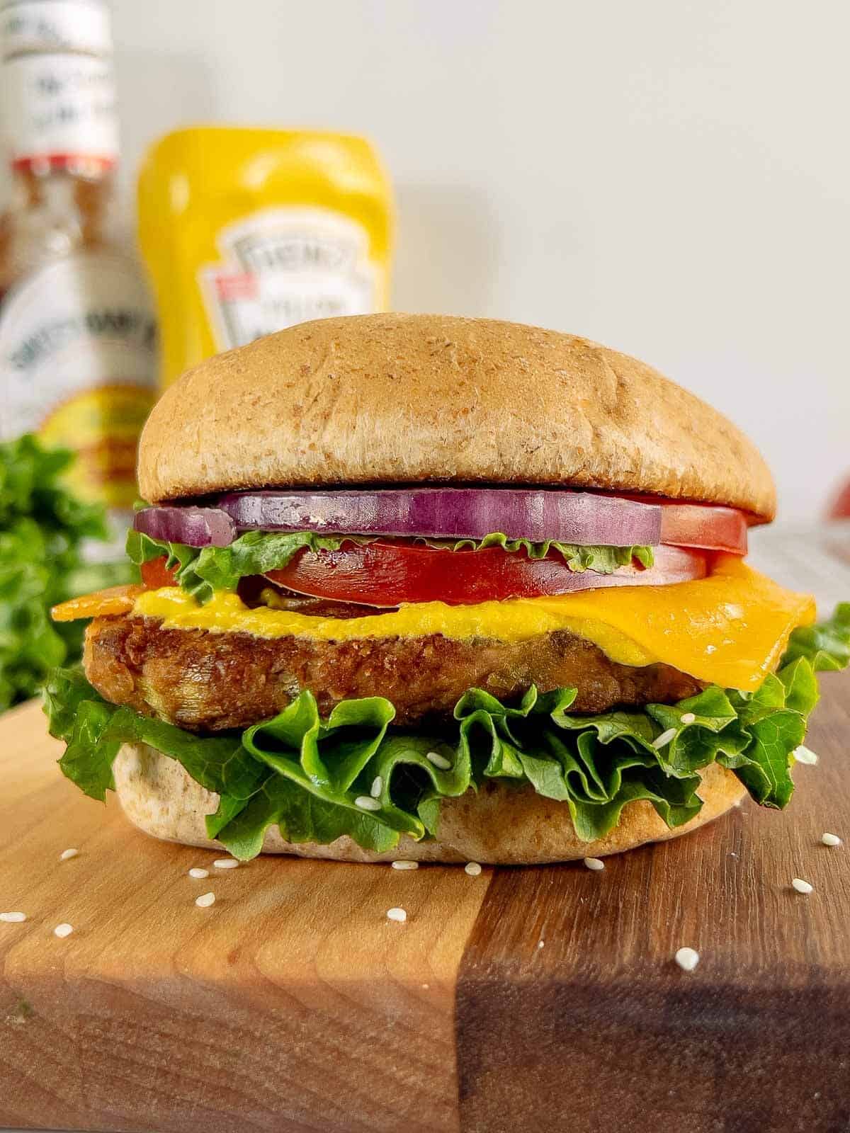 chickpea burger assembled with yellow mustard behind.