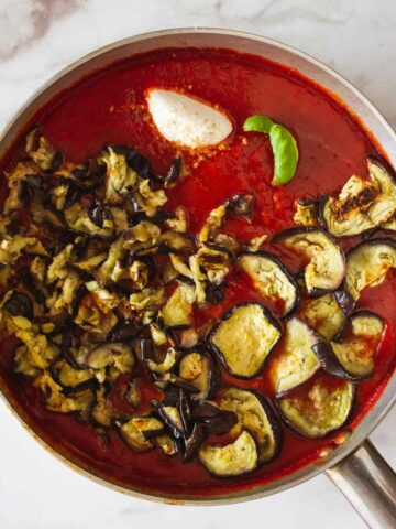 roasted eggplant slices and vegan ricotta added into the tomato sauce in the saucepan.