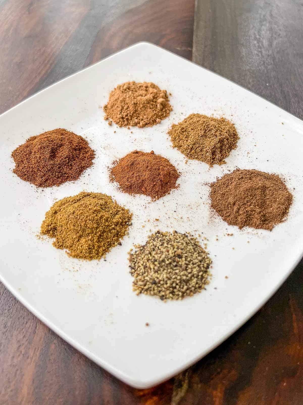 lebanese seven spices ingredients separated in a white plate.