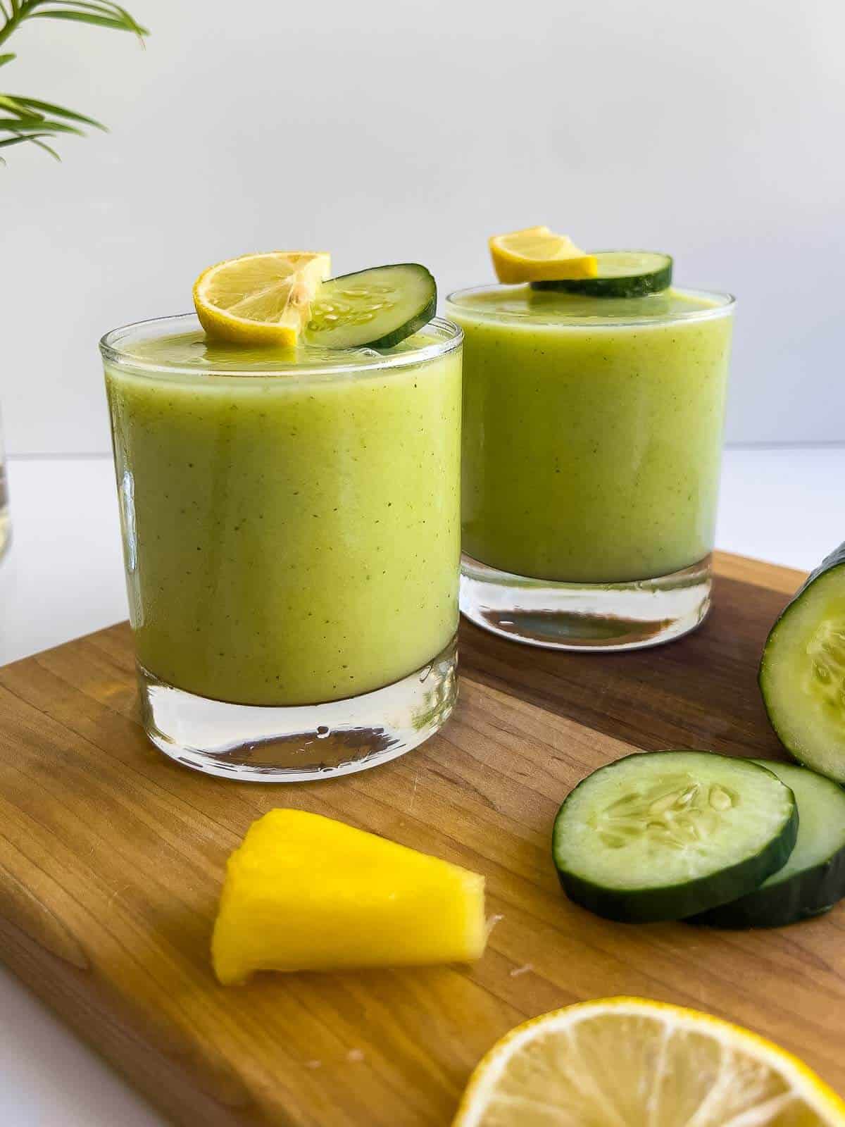 Pineapple Cucumber Smoothie served in two glasses topped with pineapple chunks and cucumber  slices