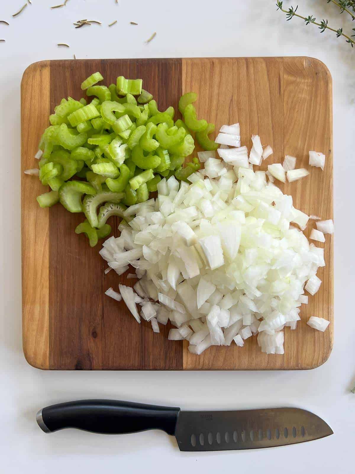 chopped onions and celery on a chopping board.