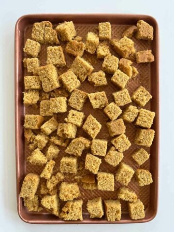 cornbread dice arranged on a non-stick baking sheet.