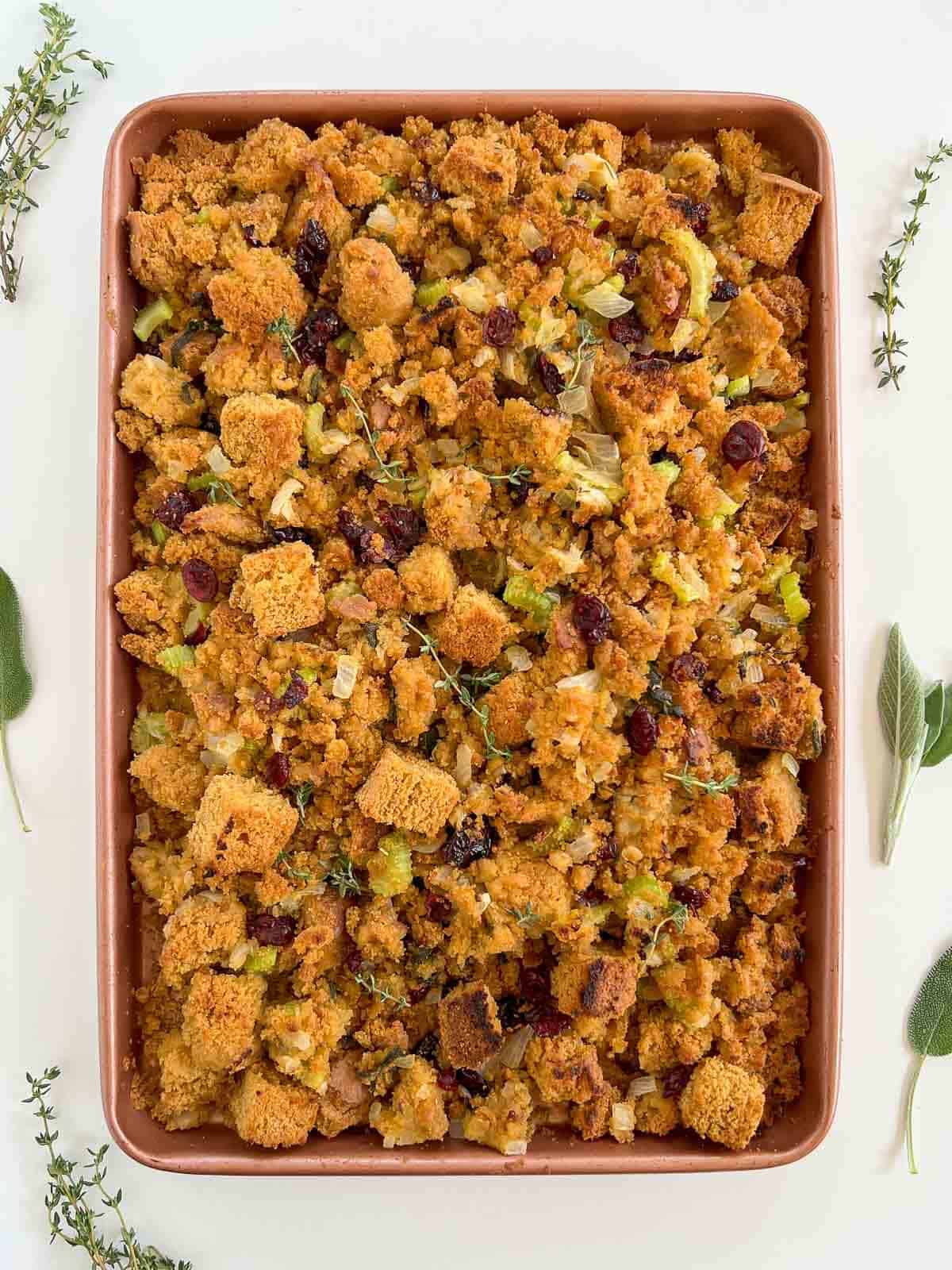 cornbread stuffing out of the oven served with thyme sprigs on top.