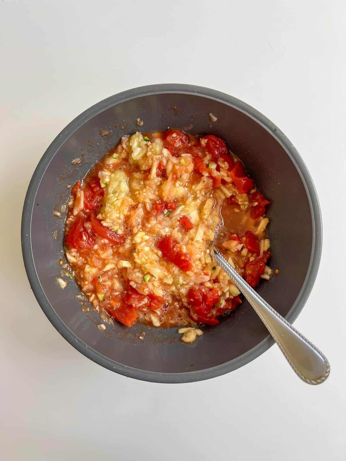 mixing tomato with zucchini flesh in bowl.