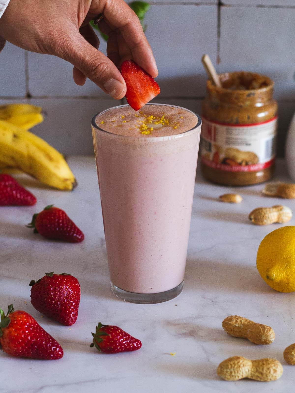 garnishing peanut butter strawberry smoothie with a fruit slice.