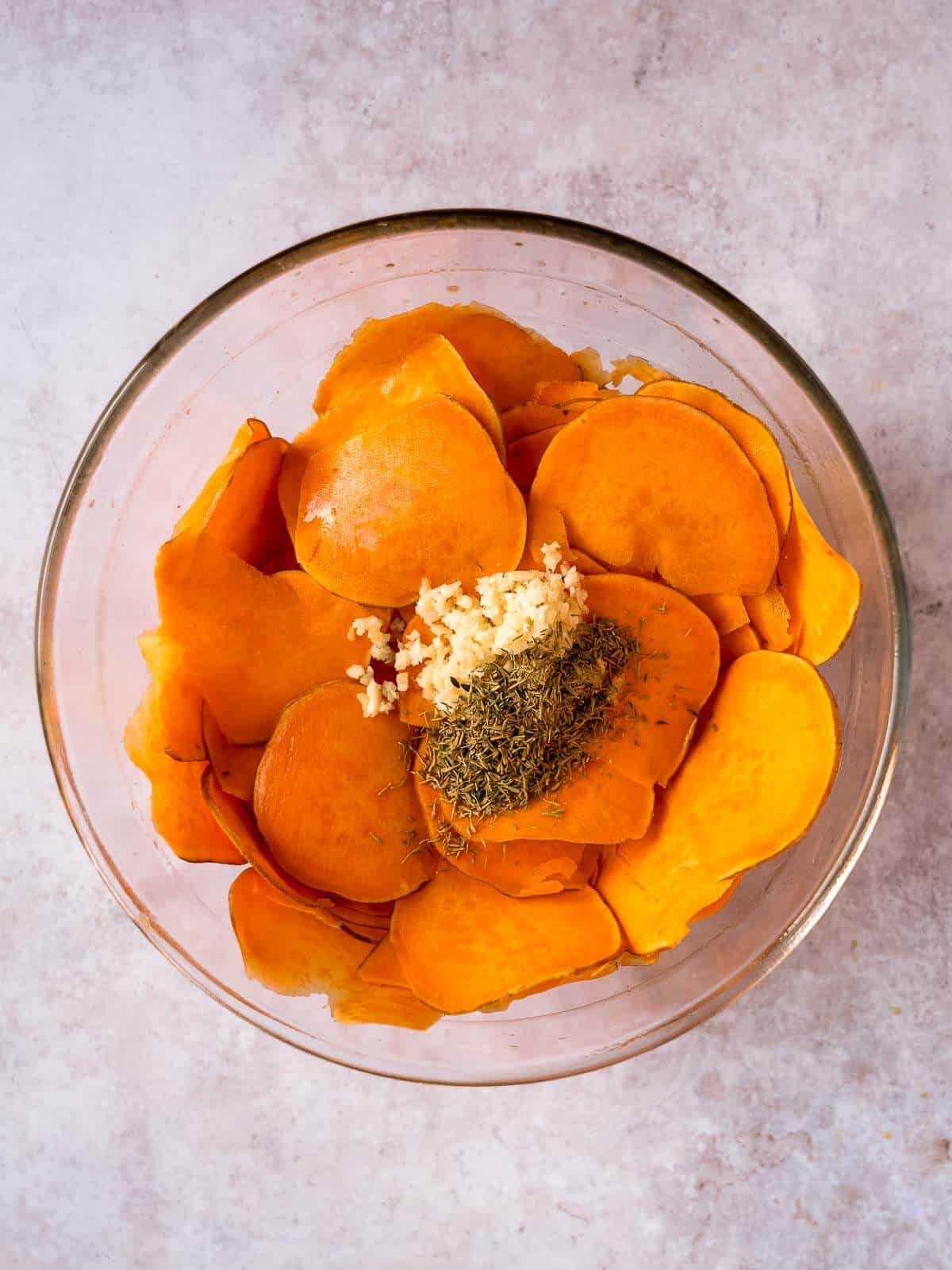 mixing bowl with sweet potato slices and all seasonings.