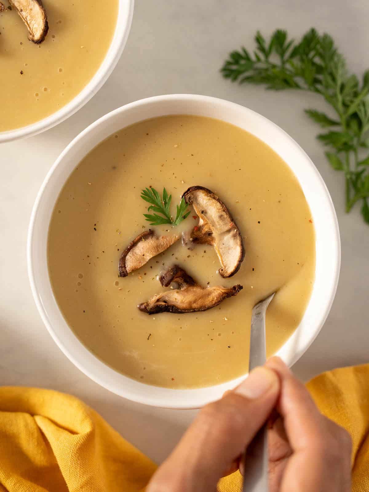 spoon with 4-ingredient potato soup garnished with sautéd mushrooms.