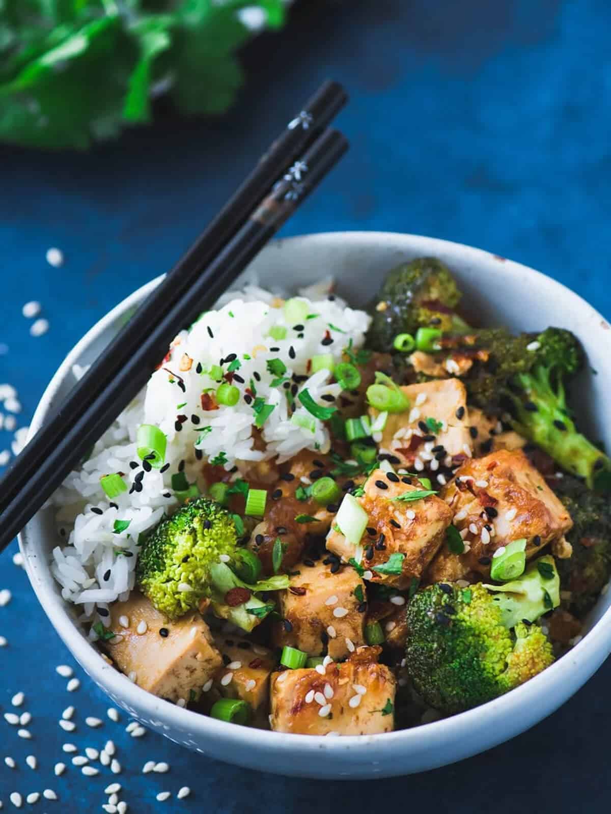 My favorite of all instant pot tofu recipes, it is made in Chinese takeout style tofu served and in white bowl with sesame seeds and chop sticks.