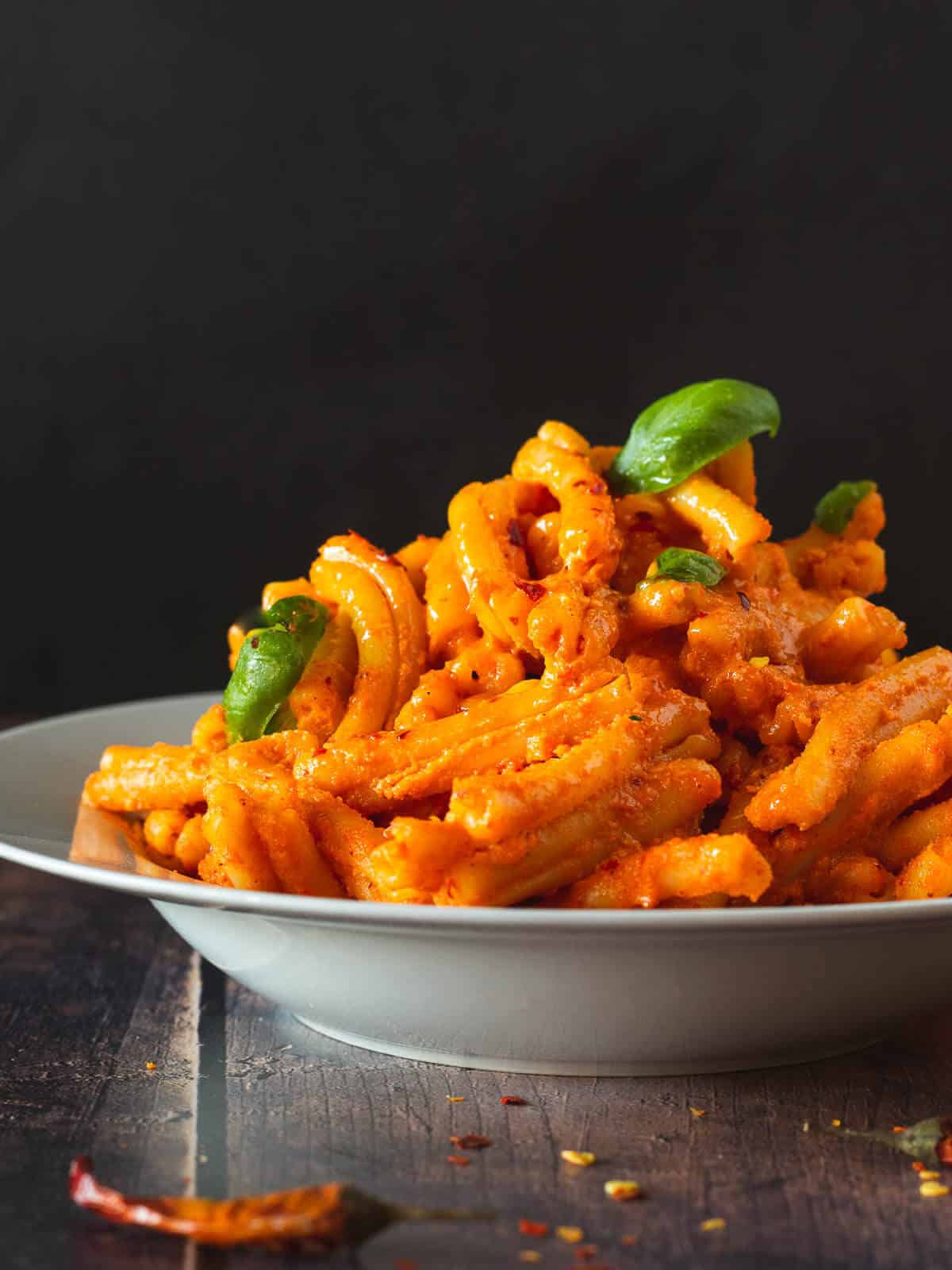 creamy past dish with red pepper tofu pesto and basil leaves.