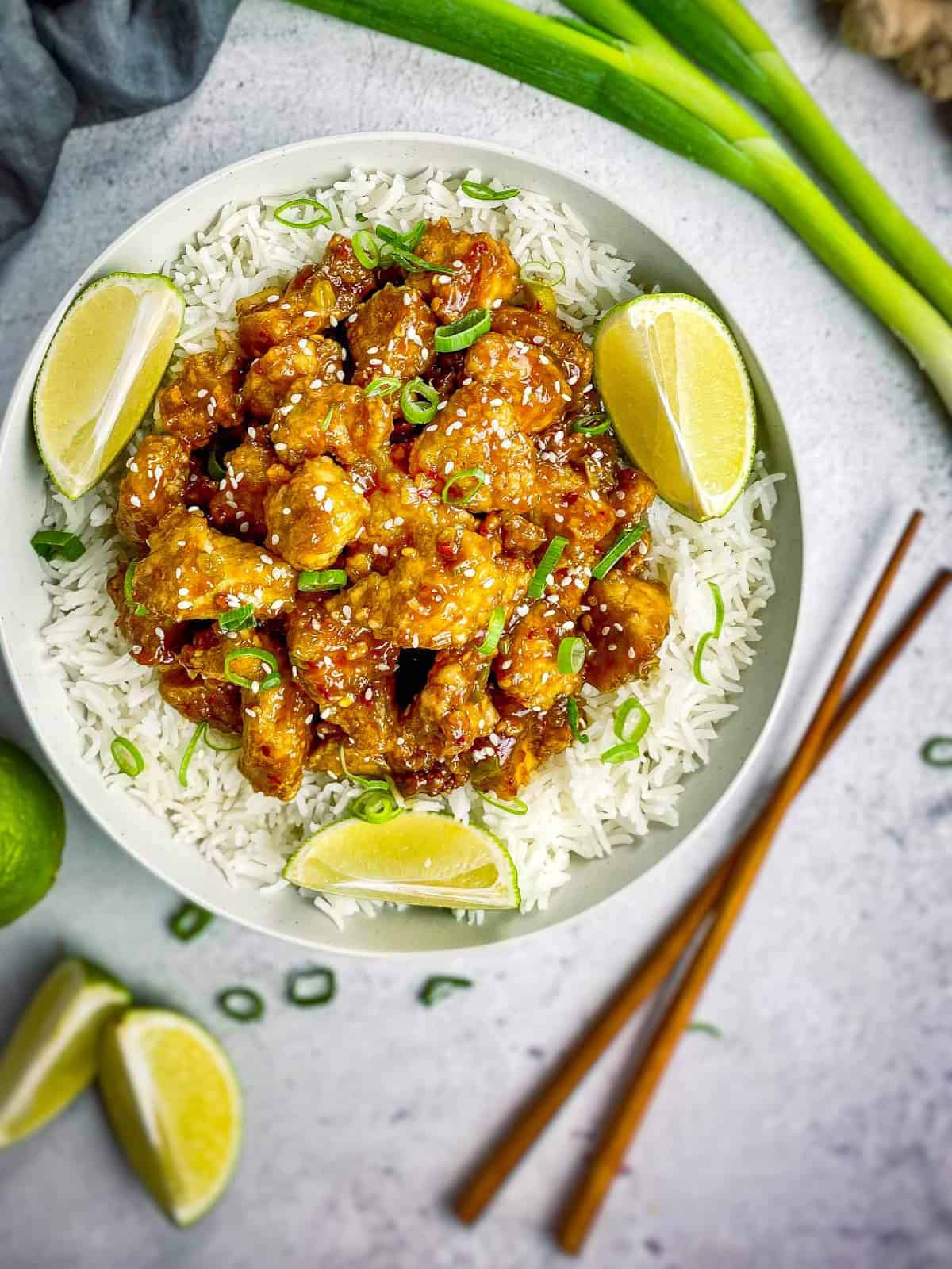 general tso tofu recipe served in flat white plate with lemon wedges.