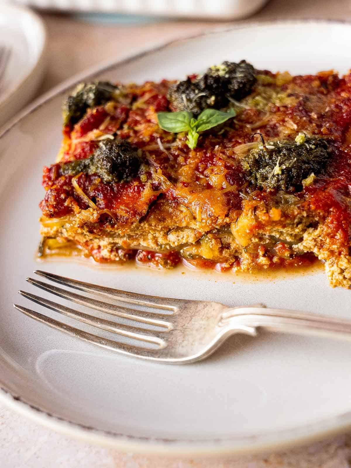 vegan gluten-free lasagna slice with sprinkled vegan parmesan cheese in a white plate.