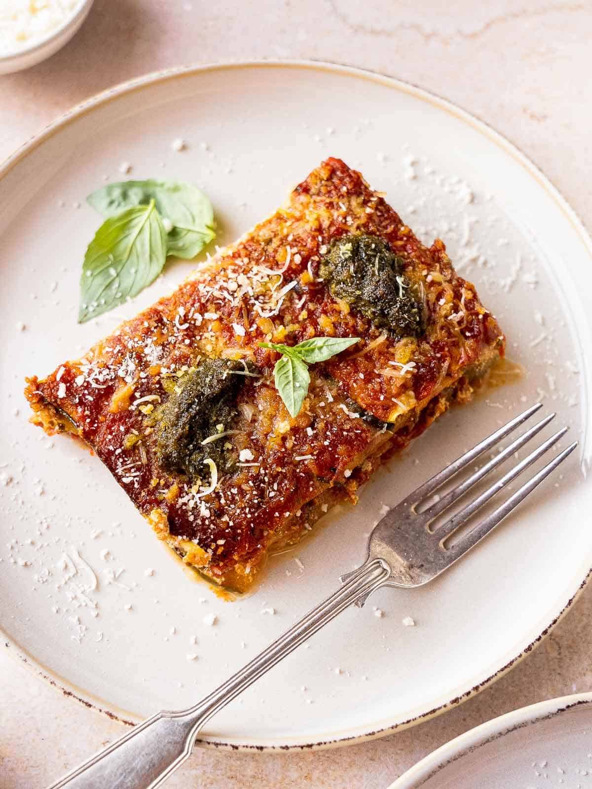 vegan zucchini casserole slice with sprinkled vegan parmesan cheese in a white plate.