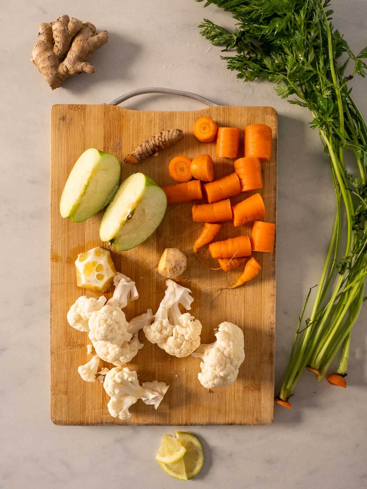 chopped carrot ginger turmeric juice ingredients chopped into medium chunks on a wooden table.