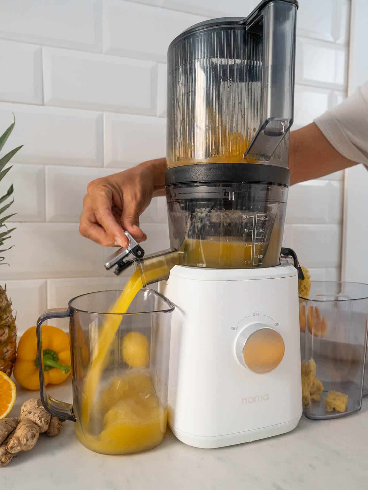 pouring Golden Pineapple and Ginger juice from the juicer.