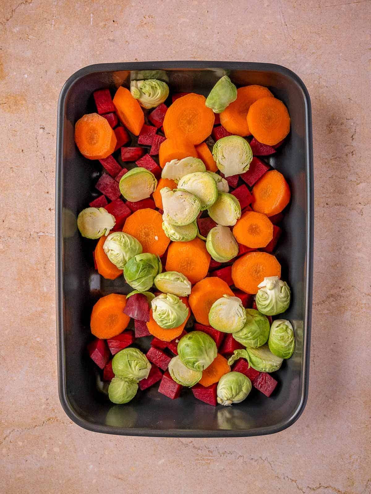 add raw chopped vegetables into a baking dish.
