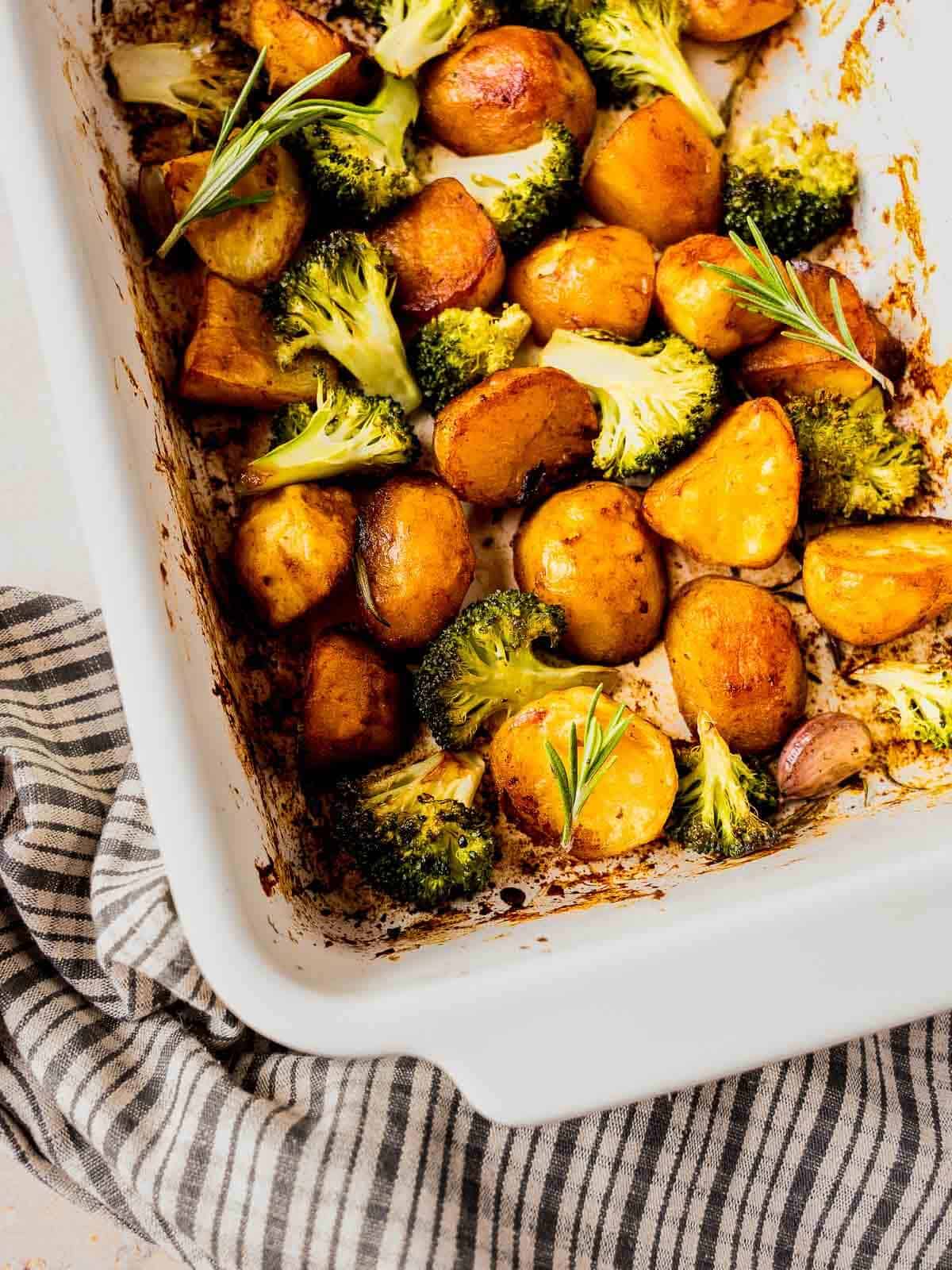 roasted garlic and rosemary potatoes with marmite in white casserole dish.
