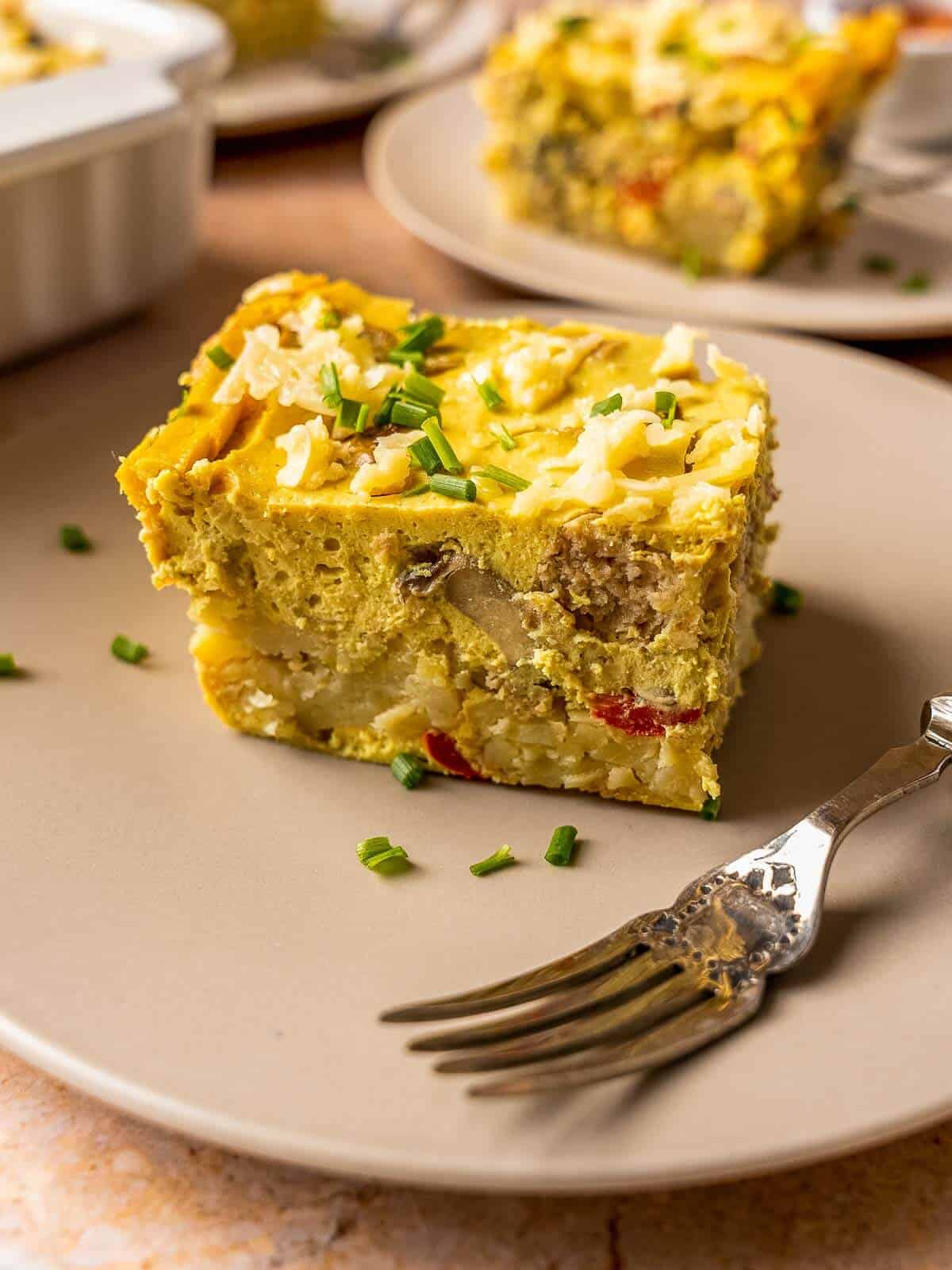 vegan breakfast casserole portion plated on a beige plate.