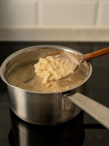 wooden spoon with rice pudding with runny texture.