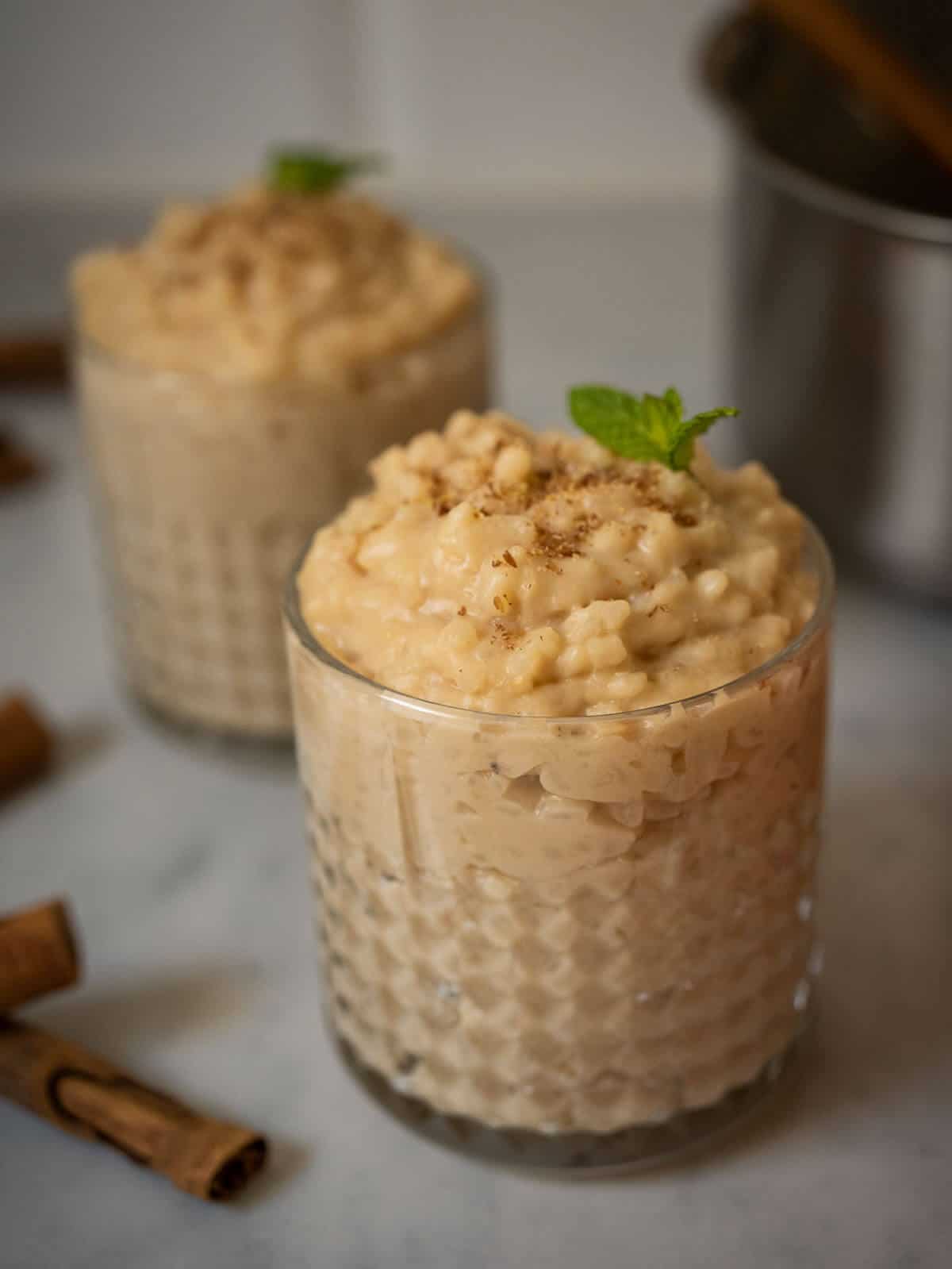 3 ingredient vegan rice pudding with oat milk with cinnamon sticks on the side.