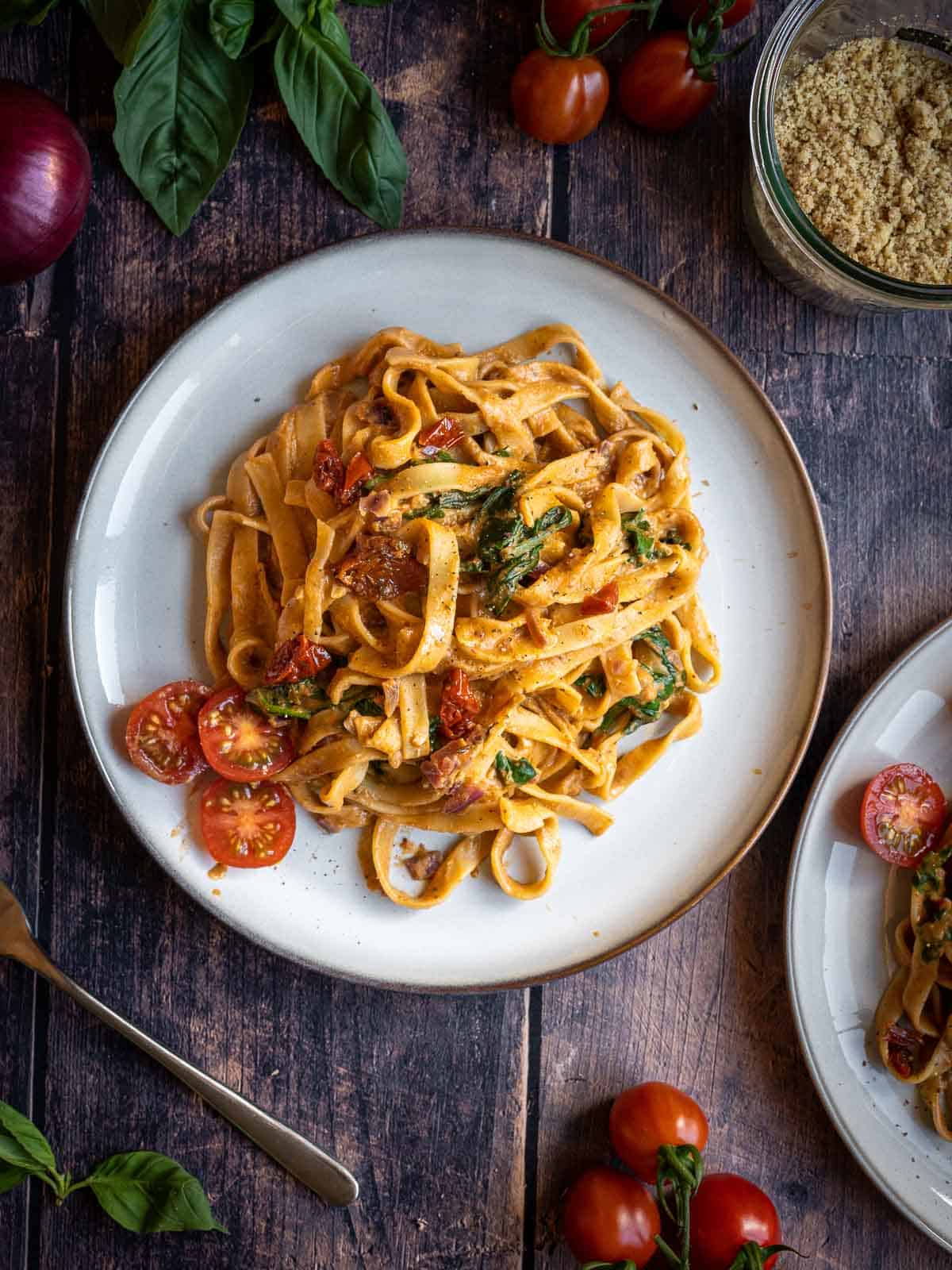 creamy  Spinach fettuccine pasta  served with halved cherry tomatoes plate.