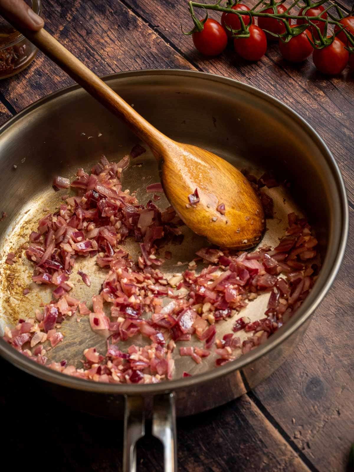 sautéeing onion in a skillet stirring with a wooden spoon.