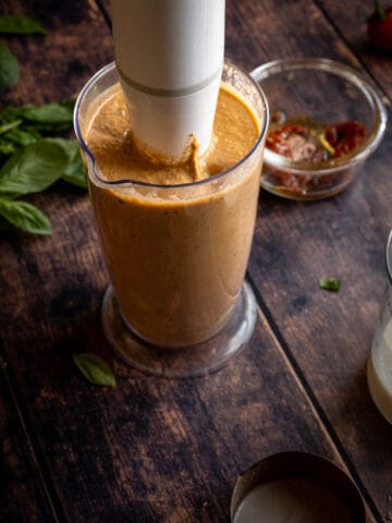 preparing creamy sauce for fettuccine pasta, blending all the ingredients of the sun dried tomato pasta sauce in an immersion blender.